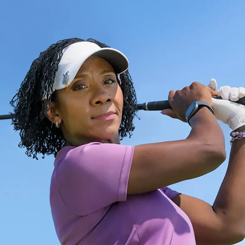 Toni swinging a golf club against a blue sky